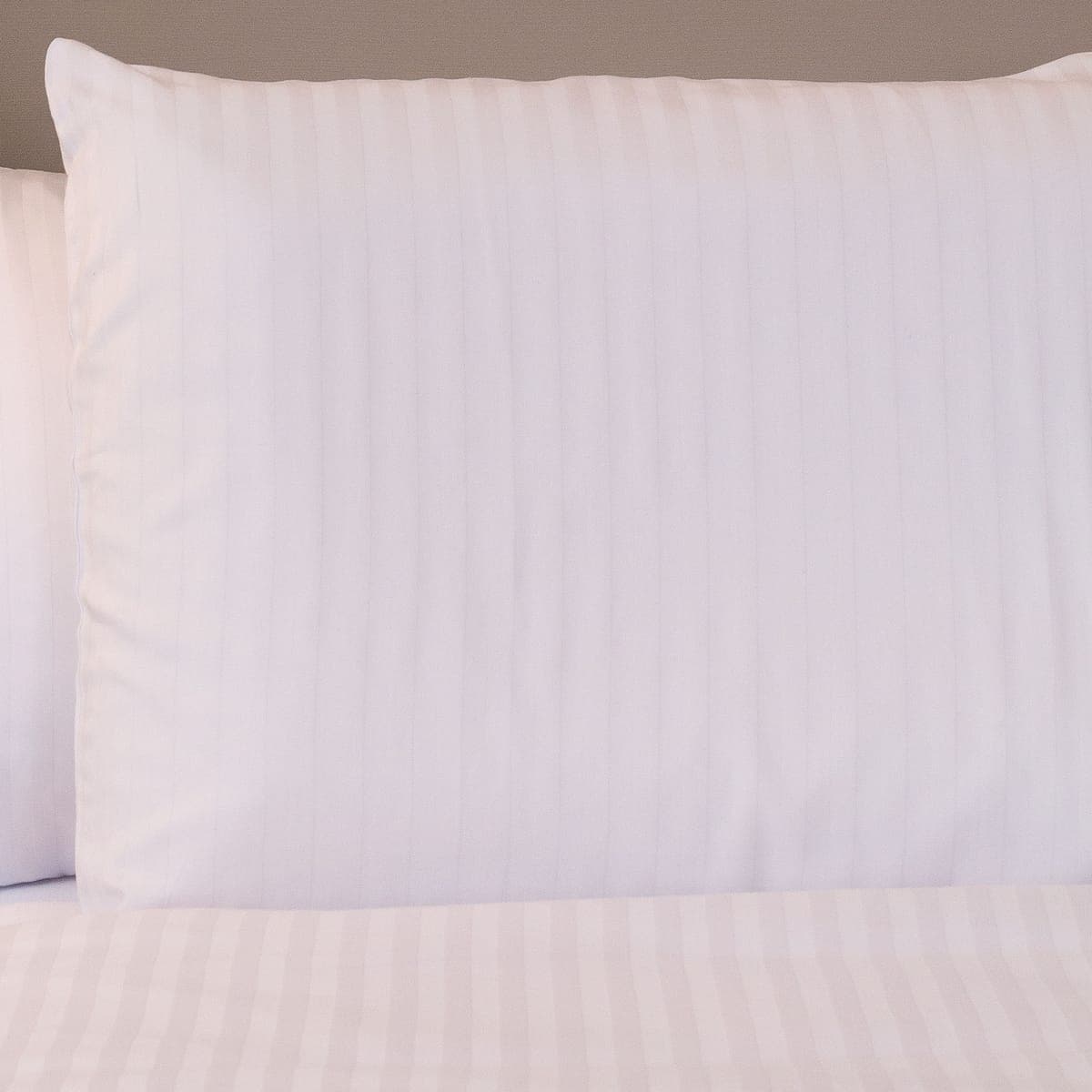 Tone-on-tone striped sateen pillowcases and sheet in a hotel room